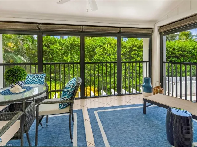 Sunroom / solarium featuring tile patterned flooring, lofted ceiling, and view of scattered trees