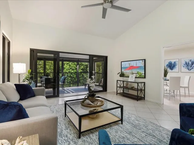 Living area with high vaulted ceiling, light tile patterned flooring, and ceiling fan