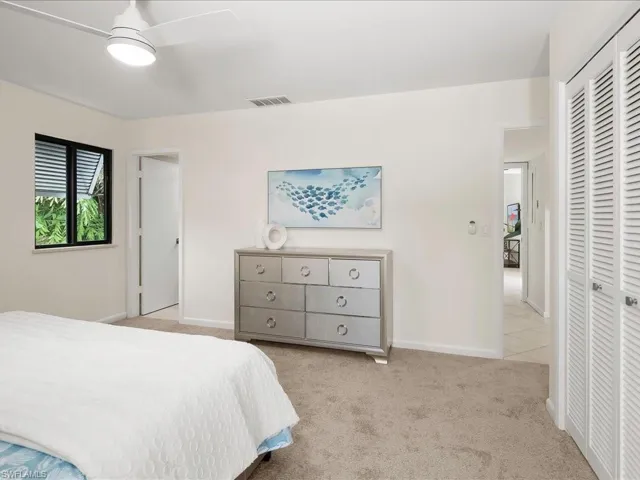 Bedroom with light carpet, a closet, and a ceiling fan