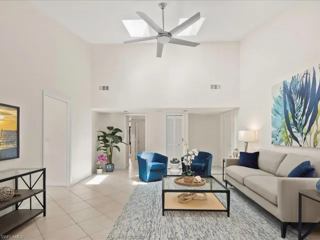 Living room featuring light tile patterned floors, a high ceiling, a skylight, and a ceiling fan