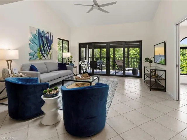 Living area with light tile patterned floors, high vaulted ceiling, healthy amount of natural light, and ceiling fan