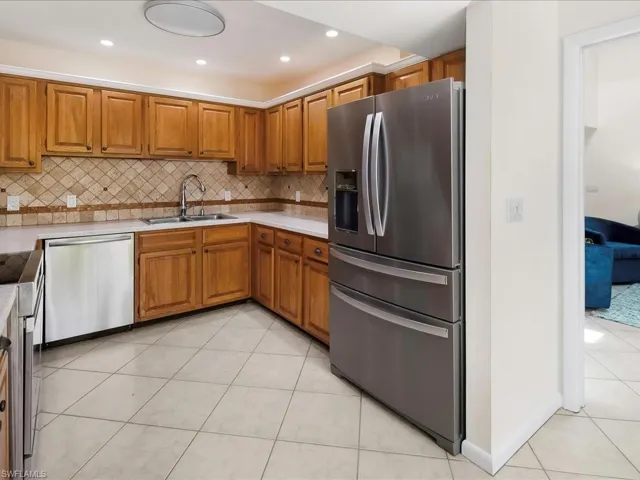 Kitchen with light tile patterned flooring, appliances with stainless steel finishes, brown cabinetry, light countertops, and recessed lighting