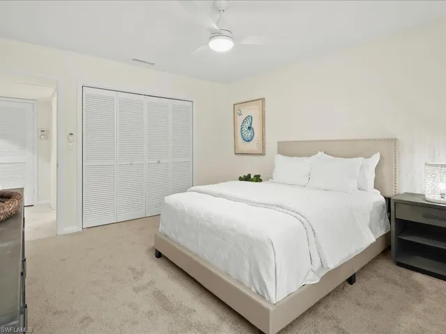 Bedroom with a closet, light colored carpet, and ceiling fan