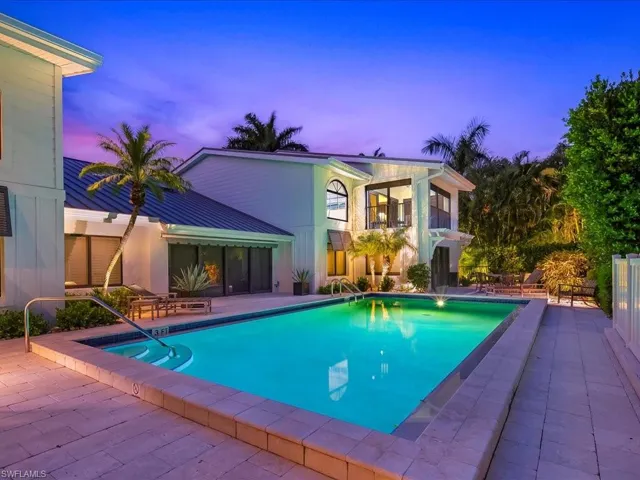 Pool at dusk featuring a patio, a balcony, and a community pool