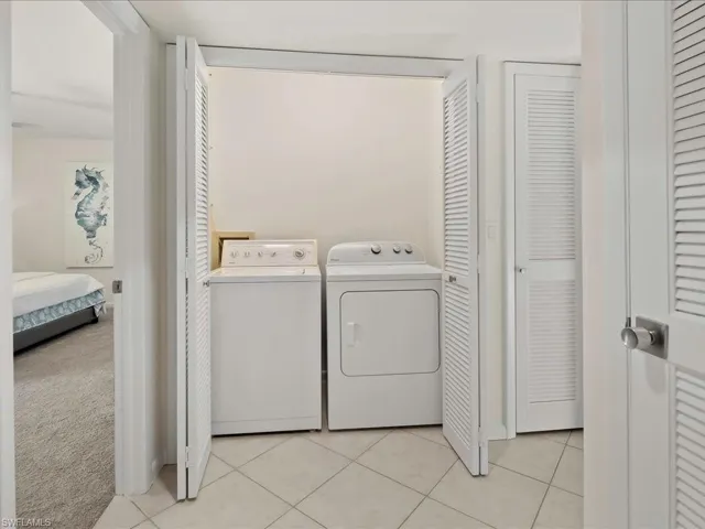 Washroom with light tile patterned floors, separate washer and dryer, and light colored carpet