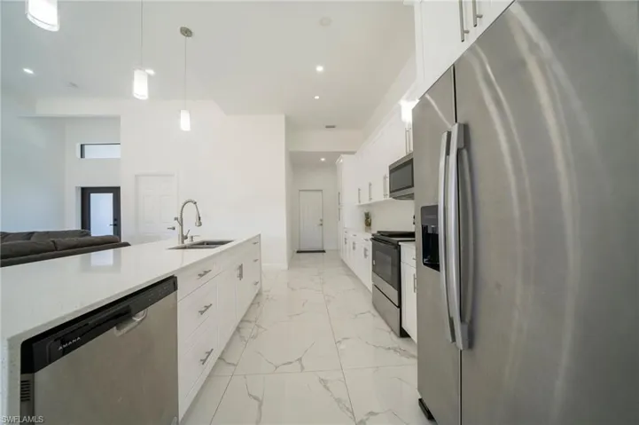 Kitchen featuring white cabinetry, sink, pendant lighting, and stainless steel appliances