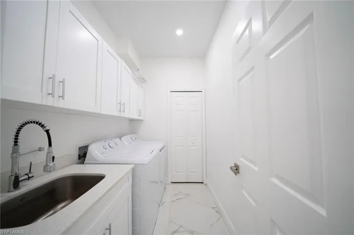 Laundry room featuring cabinets, sink, and washing machine and clothes dryer