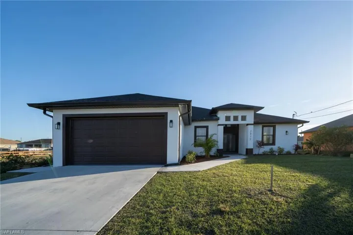 View of front of property featuring a garage and a front lawn