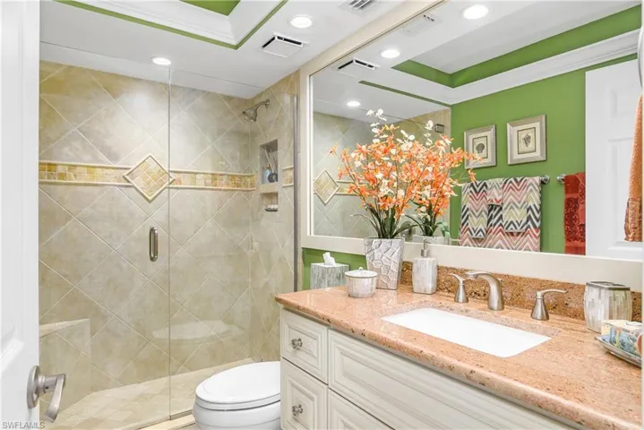Bathroom featuring walk in shower, toilet, vanity, and ornamental molding