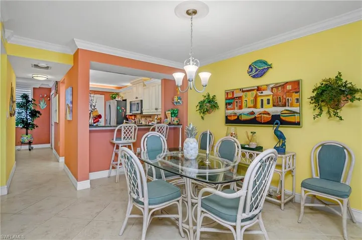 Tiled dining space featuring ornamental molding and a notable chandelier