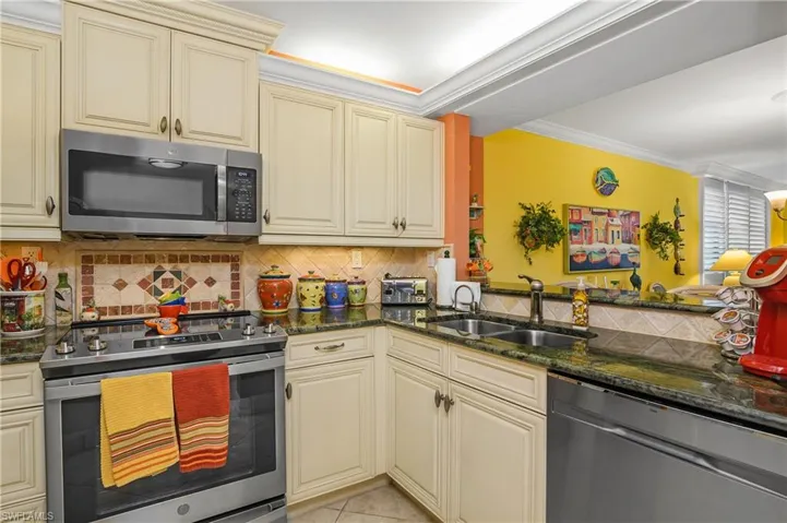 Kitchen featuring tasteful backsplash, cream cabinetry, stainless steel appliances, sink, and ornamental molding