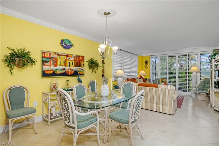 Tiled dining space featuring an inviting chandelier and crown molding