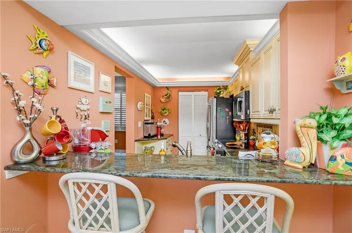 Kitchen with a tray ceiling, crown molding, dark stone counters, and cream cabinetry