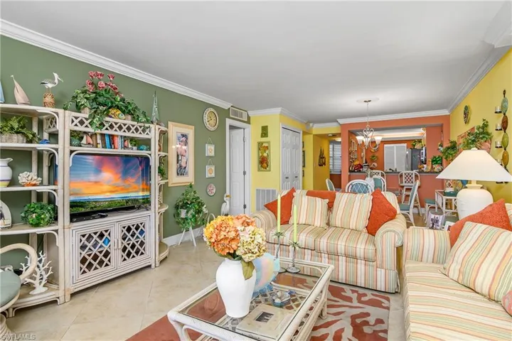 Living room featuring a notable chandelier, light tile patterned floors, and ornamental molding