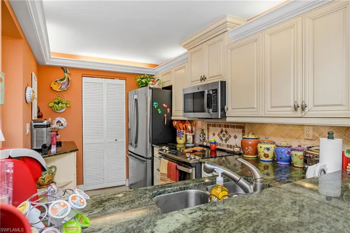 Kitchen featuring decorative backsplash, appliances with stainless steel finishes, sink, and cream cabinets