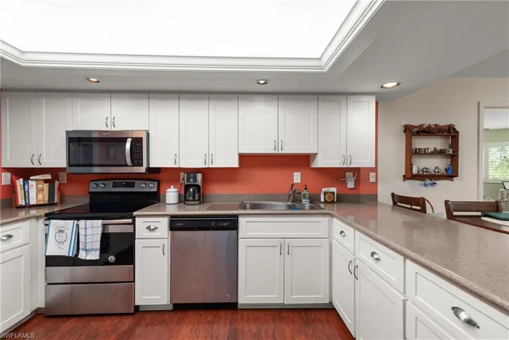 Kitchen with appliances with stainless steel finishes, recessed lighting, a sink, white cabinets, and dark wood-style floors