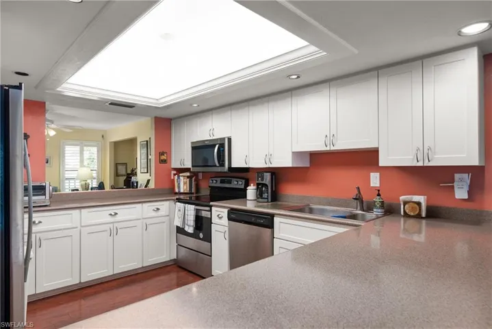 Kitchen with appliances with stainless steel finishes, recessed lighting, white cabinets, a sink, and dark wood-type flooring