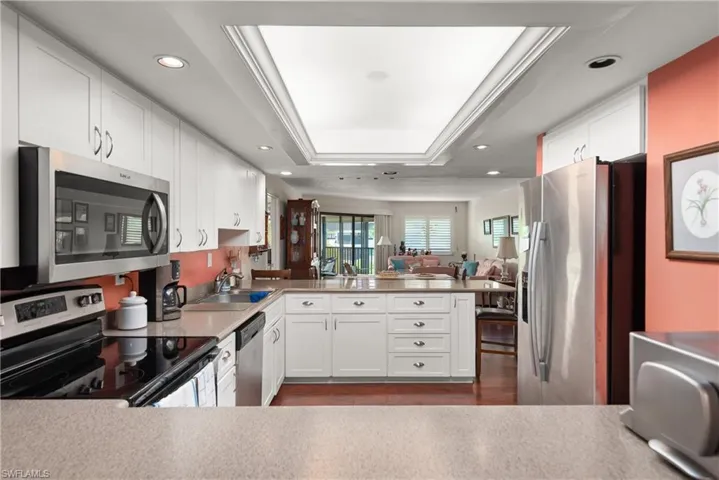 Kitchen with stainless steel appliances, a sink, a peninsula, recessed lighting, and a tray ceiling