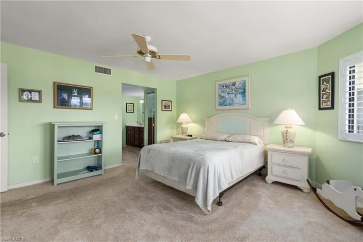 Carpeted bedroom with baseboards, connected bathroom, and ceiling fan