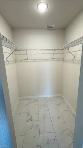 Walk in closet featuring light marble finish floors