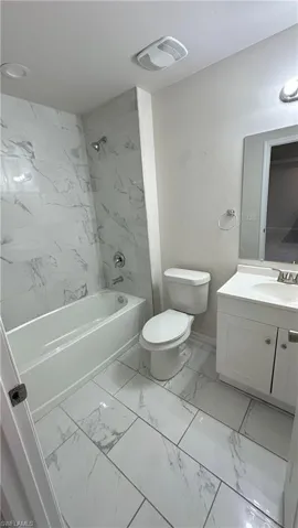 Bathroom with vanity, light marble finish flooring, and shower / bath combination