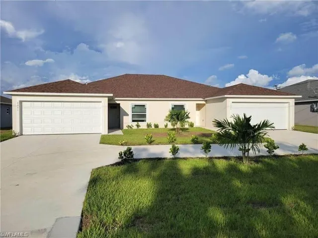 Ranch-style home featuring an attached garage, a front yard, driveway, and stucco siding