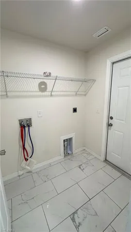 Laundry room with hookup for a washing machine, light marble finish floors, and hookup for an electric dryer