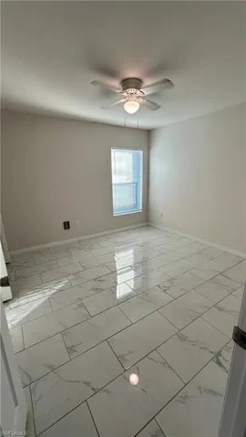 Empty room featuring light marble finish flooring and ceiling fan