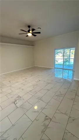 Spare room featuring light marble finish flooring and ceiling fan