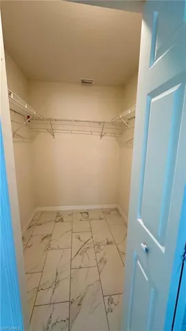 Walk in closet with light marble finish flooring