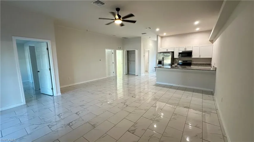 Unfurnished living room with a ceiling fan, light marble finish floors, and recessed lighting