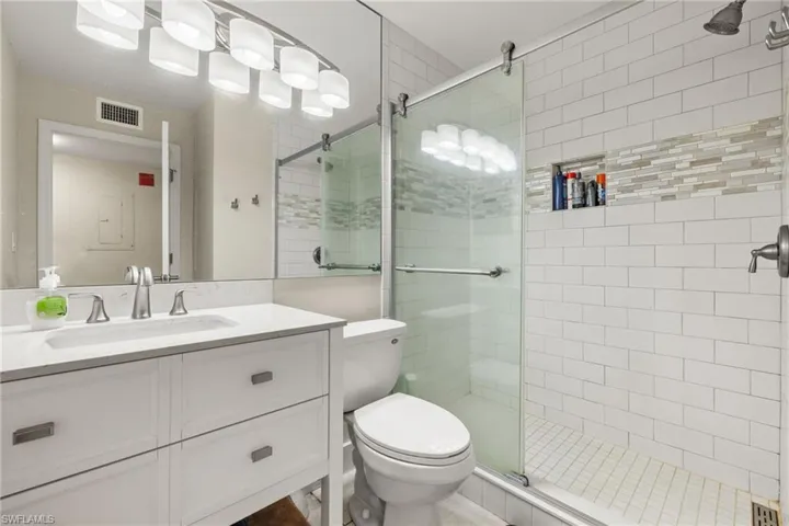 Bathroom with a shower with shower door, vanity, and toilet