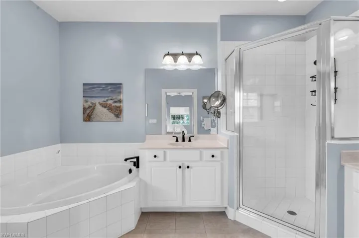 Bathroom with tile patterned floors, vanity, and independent shower and bath