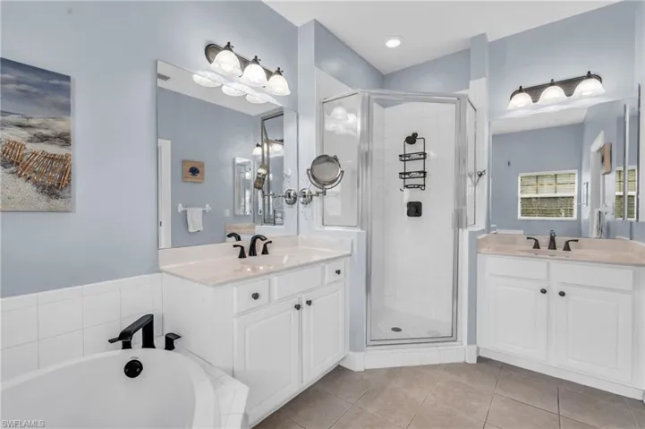 Bathroom featuring tile patterned floors, vanity, and shower with separate bathtub