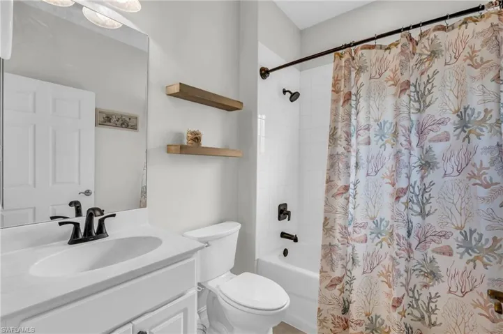 Full bathroom featuring shower / bath combo with shower curtain, vanity, and toilet