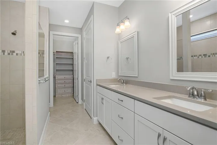 Bathroom featuring a tile shower, vanity, and tile patterned floors