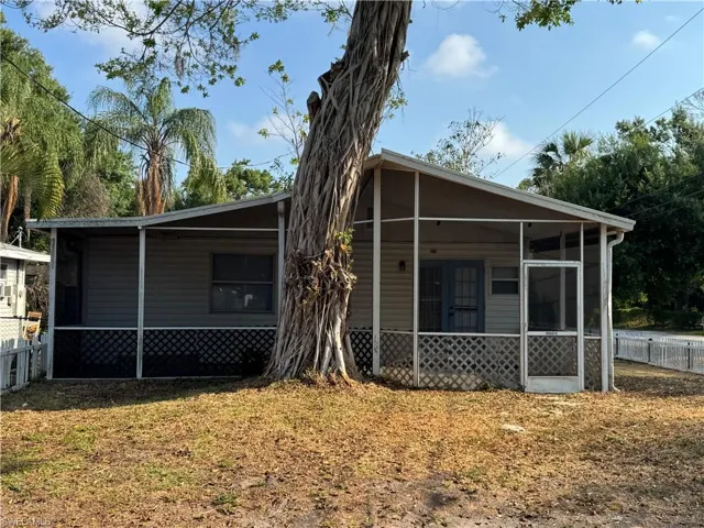 View of front of house featuring fence, a sunroom, and a front lawn