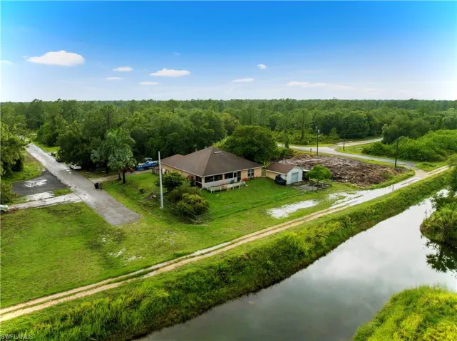 View of subject property with a nearby body of water and a forest