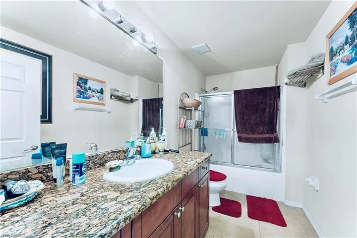 Bathroom featuring vanity, shower / bath combination with glass door, and tile patterned flooring