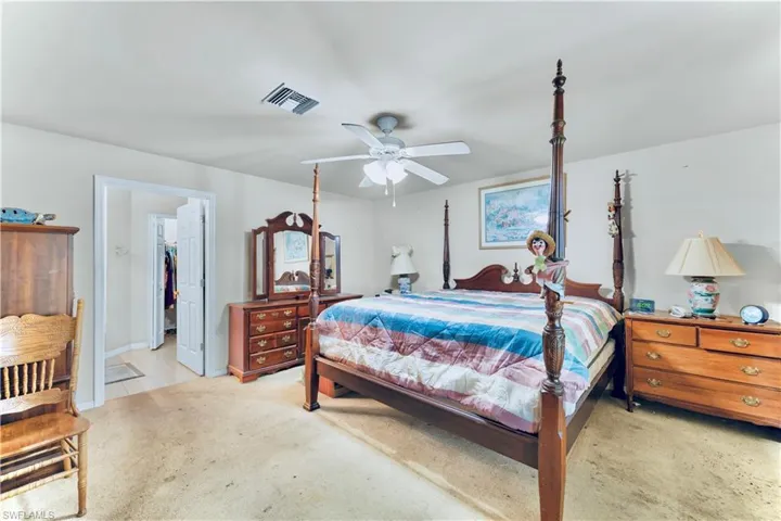 Bedroom with light carpet, ceiling fan, and a walk in closet