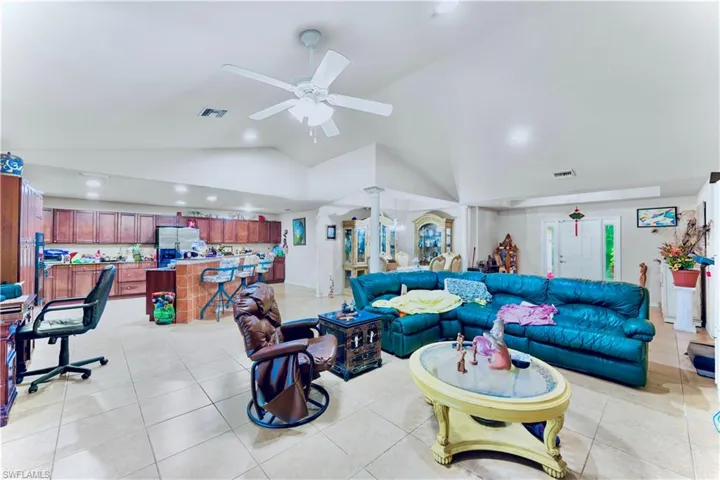 Living area with ceiling fan, light tile patterned flooring, vaulted ceiling, and recessed lighting