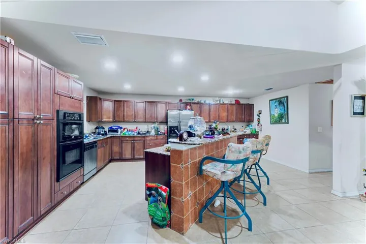 Kitchen featuring appliances with stainless steel finishes, light tile patterned flooring, a kitchen breakfast bar, recessed lighting, and a kitchen island