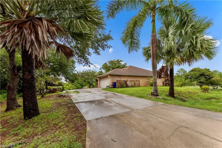 View of front of property featuring concrete driveway, a front yard, an attached garage, and stucco siding