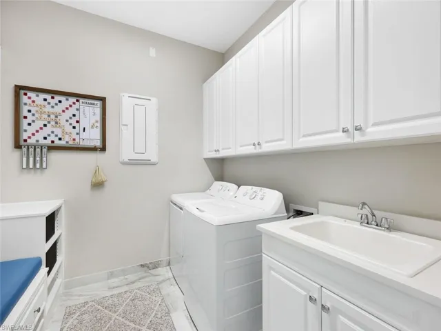 Laundry room with cabinets, separate washer and dryer, and sink