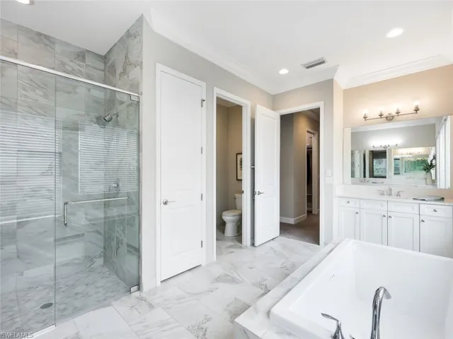 Full bathroom featuring plus walk in shower, toilet, vanity, and ornamental molding
