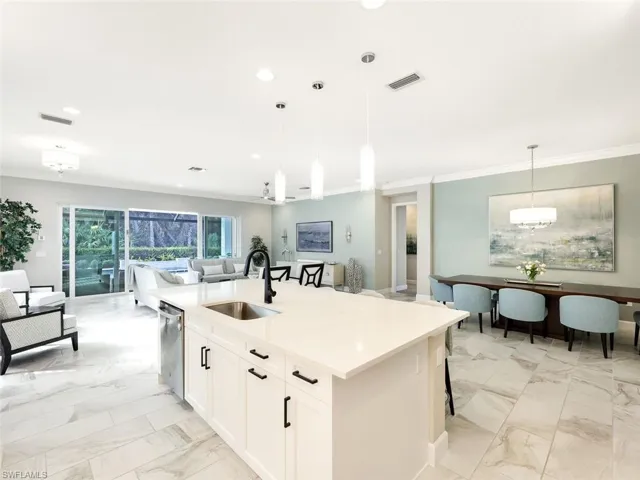 Kitchen featuring white cabinetry, sink, dishwasher, pendant lighting, and a kitchen island with sink