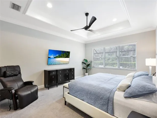 Bedroom with ornamental molding, a tray ceiling, ceiling fan, and light colored carpet