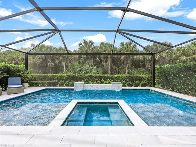 View of pool with an in ground hot tub and glass enclosure