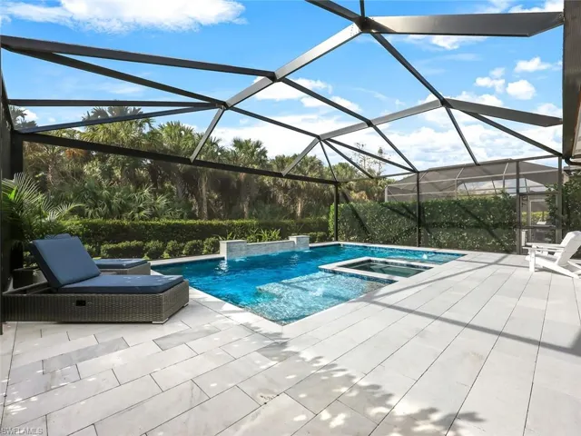 View of pool with a lanai, a patio area, an in ground hot tub, and pool water feature