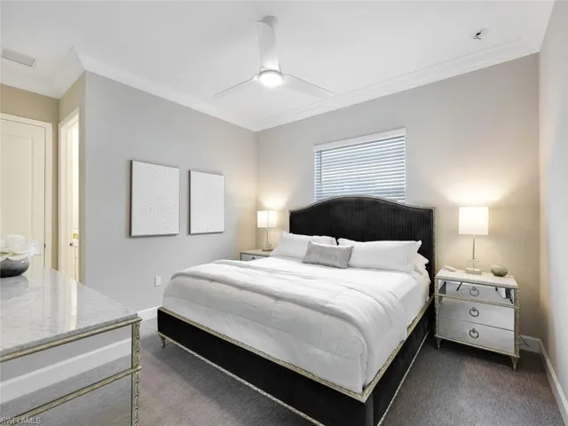 Bedroom with ceiling fan, dark carpet, and ornamental molding